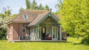 Ein kleines Backsteinhaus mit einer Veranda, einem Esstisch und einem roten Sofa.