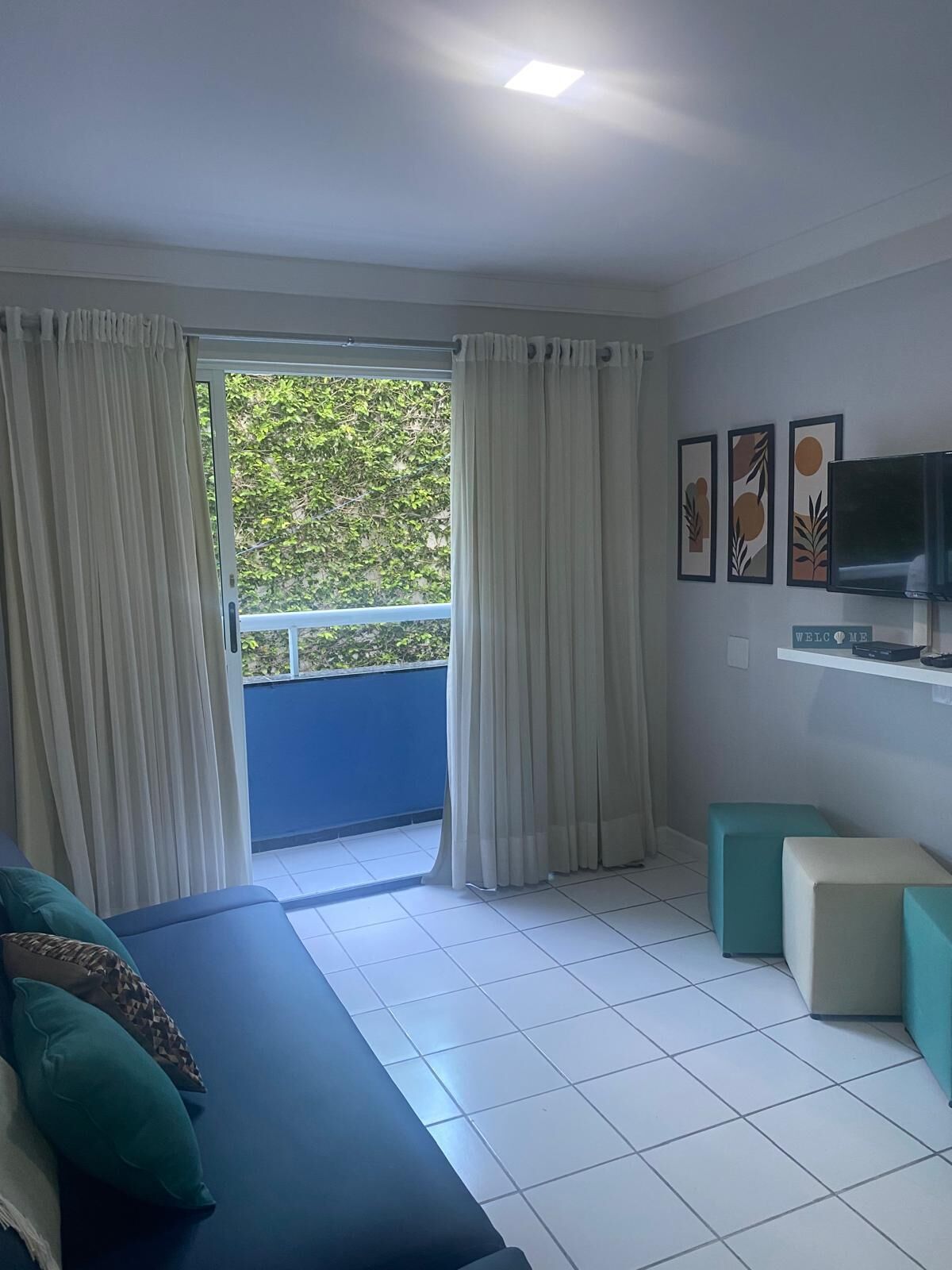 Une chambre avec un lit, une télévision et un balcon avec des rideaux.