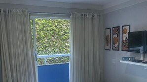A room with a bed, a TV, and a balcony with curtains. - Ponta Negra Beach EFM - 323 (Natal)