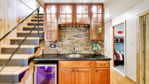 A kitchen with wooden cabinets, a stone backsplash, and a black countertop.