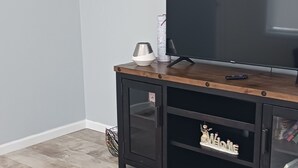 Ein Wohnzimmer mit einer Holz-Unterhaltungsanlage, einem Flachbildfernseher und einem dekorativen Wandkunstwerk mit Schmetterlingen.