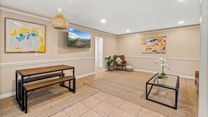 A room with a bench, a glass coffee table, and two abstract paintings.