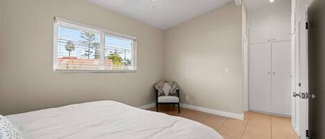 A bedroom with a bed, a ceiling fan, a window, a chair, and a wardrobe.