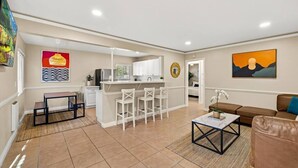 A modern living room with a kitchen area, a dining table, and a sofa.