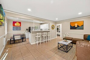 A modern living room with a kitchen area, a dining table, and a sofa.