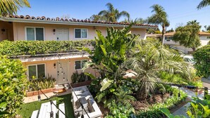 A residential property with a patio, outdoor seating, and lush vegetation.