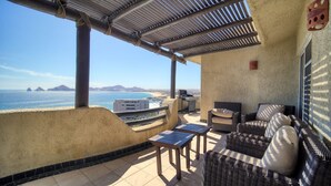 A covered outdoor seating area with wicker furniture, a table, and a view of the ocean. - MILLION DOLLAR VIEW PENTHOUSE 2BDR, 2 BTH  (Cabo San Lucas)