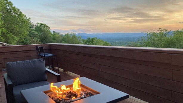 A deck with a built-in fire feature, seating, and a view of mountains. - Gorgeous mountain view - 3 minutes from Downtown Asheville (Asheville)