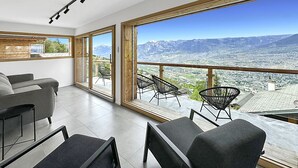 En rummelig stue med balkon, store vinduer og bjergudsigt.