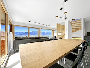 Una cocina moderna con una mesa de madera, asientos integrados y amplios ventanales con vistas a la montaña.