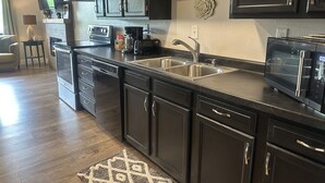 A modern kitchen with dark cabinetry, stainless steel appliances, and a built-in microwave. - Deer Ridge Duplex - Beautiful Lake View with Shared Dock! (Sunrise Beach)