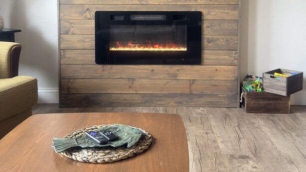 A living room with a wooden fireplace, a mounted TV, and a comfortable seating area. - Deer Ridge Duplex - Beautiful Lake View with Shared Dock! (Sunrise Beach)