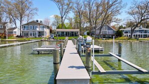 A waterfront property with a dock, a pool, and houses in the background.