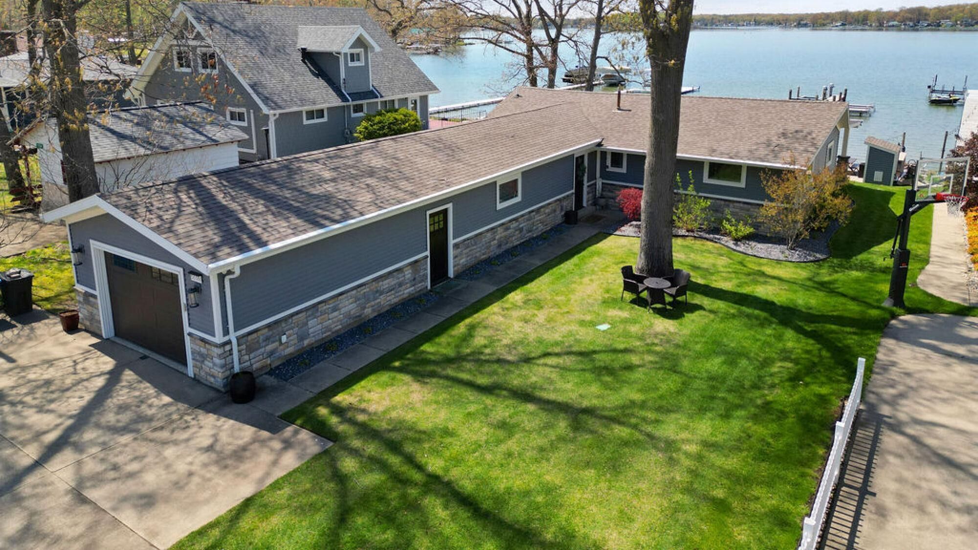Ein Wohnhaus mit Garage, einem gepflegten Rasen und Seeblick.