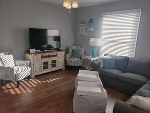 Relax in this inviting living room with a sofa, armchair, and flat-screen TV.
