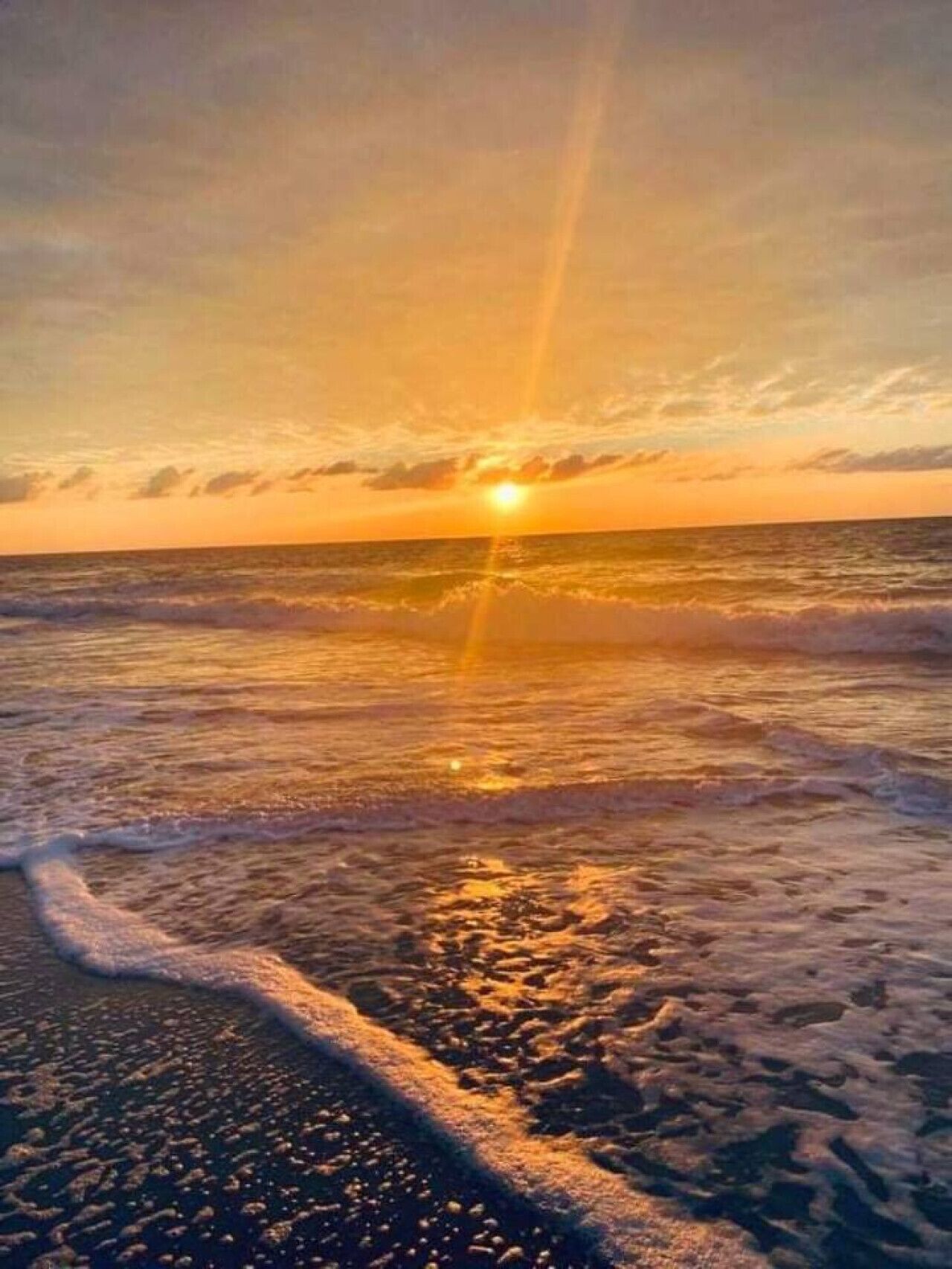 A beach at sunset with waves gently lapping the shore.