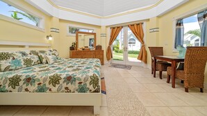 Une chambre à coucher comprenant un lit, une commode et un coin repas avec des chaises et une table en osier.