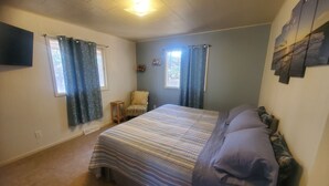 A bedroom with a bed, a chair, a window, and a wall-mounted TV. - Lake Delton ~ Wisconsin Dells Home Provides Comfort and Access to All Activities (Wisconsin Dells)