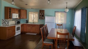 A compact kitchen with wooden cabinets, a white refrigerator, and a dining table with chairs. - Lake Delton ~ Wisconsin Dells Home Provides Comfort and Access to All Activities (Wisconsin Dells)