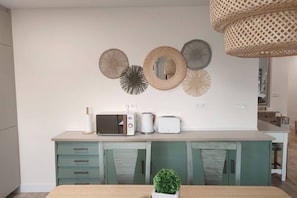 A kitchen with a microwave, toaster, and kettle on the counter, and decorative wall art above. - 178A Mar de Gijón: Apartment with Views by R2R (Gijón)