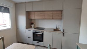 Eine kleine Küche mit Backofen, Spüle und einem Fenster mit Jalousien.