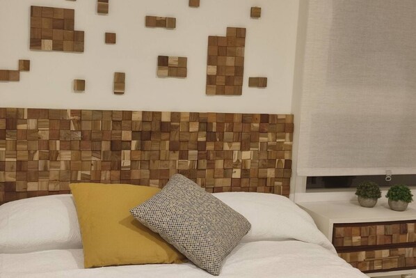 A bed with a white headboard, a yellow pillow, and a checkered pillow.
