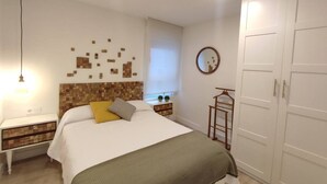 Ein Schlafzimmer mit einem Bett, Nachttischen, einem Kleiderschrank, einem Spiegel und einer Wanddekoration.