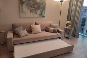 A modern living room with a sofa, pillows, a floor lamp, and a painting on the wall.