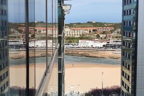 A view from a high-rise building overlooking a beach with buildings and a sign in the distance.