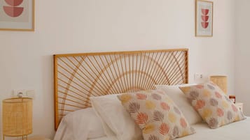 Un letto con una testiera in legno, due cuscini decorati, una lampada da comodino e un interruttore della luce fissato al muro.