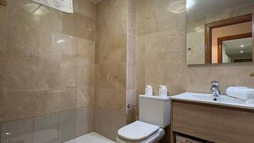 Een badkamer met toilet, wastafel en spiegel.