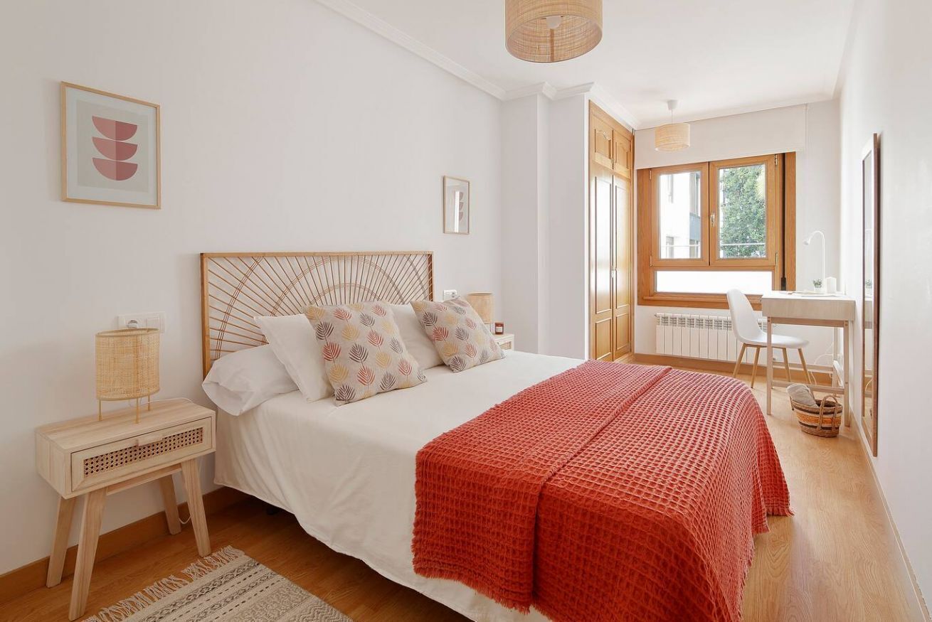Een slaapkamer met een bed, nachtkastjes, een bureau en een raam.