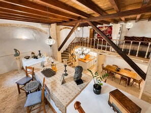 A spacious room with a high ceiling, a staircase, a dining area, and a kitchen. - Venetian Palace Chania (Chania)