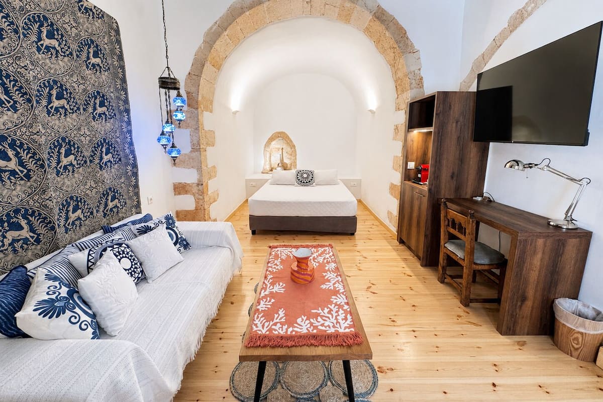 Um quarto acolhedor com uma cama, um sofá, uma TV e uma mesa de centro.