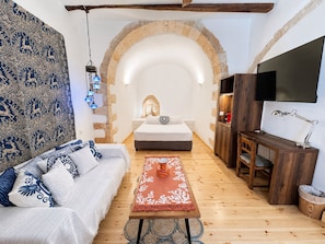 A cozy room with a bed, a sofa, a TV, and a coffee table. - Venetian Palace Chania (Chania)