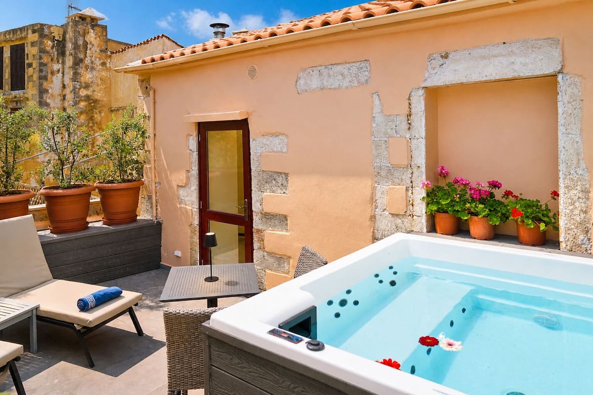 Área de piscina no terraço com hidromassagem, espreguiçadeiras e plantas em vasos.