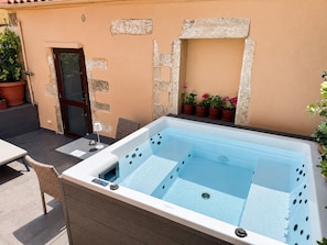 A hot tub with a wooden deck, a door, and potted plants. - Venetian Palace Chania (Chania)