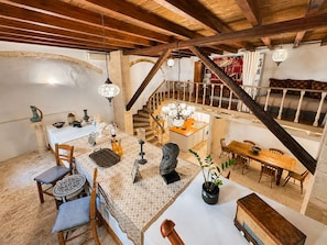 Um quarto espaçoso com teto alto, escada, área de refeições e cozinha.