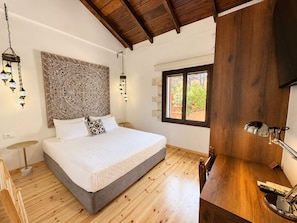 Ein Schlafzimmer mit einem Bett, Holzboden, einer Wandverkleidung, einem Fenster und einer Holzbalkendecke.