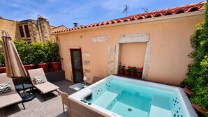 Un área de spa con hidromasaje, sillones de descanso y plantas en macetas.
