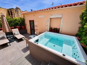 A spa area with a hot tub, lounge chairs, and potted plants.