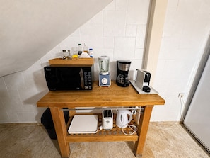 Eine Küchenarbeitsplatte mit Mikrowelle, Kaffeemaschine, Mixer und Wasserkocher.
