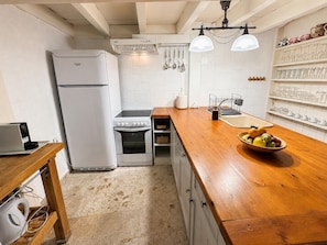 A compact kitchen with a refrigerator, stove, and wooden countertop. - Venetian Palace Chania (Chania)