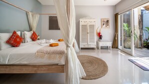A bedroom with a canopy bed, a white wardrobe, a small table, and a view of the outdoors.