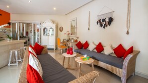 A living room with wicker sofas, red cushions, a small round table, and a white cabinet.