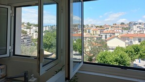Una stanza con un'ampia finestra che si affaccia su una veduta della città, con diversi edifici e alberi.