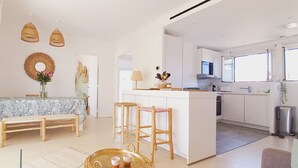 Una cucina moderna con mobili bianchi, un'area pranzo con tavolo e sedie, e un'ampia finestra.