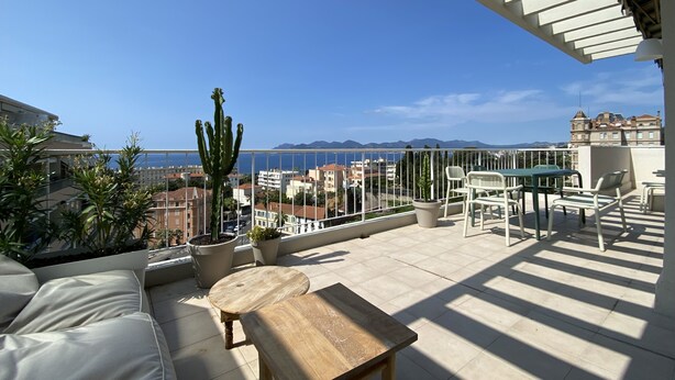 Un balcone con vista sul mare, un cactus e un tavolo con sedie.