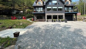 A two-story house with a stone facade, large windows, and a gravel driveway. - The Rowanwood - Muskoka Cottage Retreat (Huntsville)