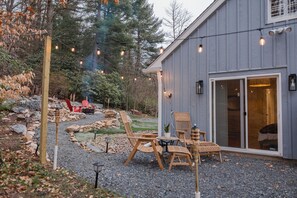 A building with a gravel patio, outdoor seating, and string lights. - Cowry Acres - The First House Villa (New Hope)